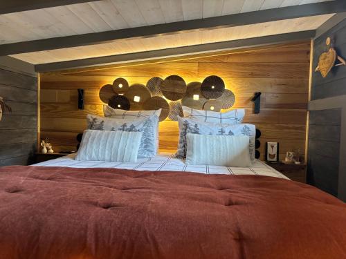 a bedroom with a large bed with a wooden wall at TiNY HOUSE LE CHALET LIT KING SIZE -TERRASSE - PETIT DÉJEUNER-CLIMATISATION -PARKING in Échenoz-la-Méline