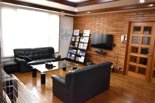 a living room with black leather furniture and a tv at A large house with a beautifui Japanese-style room in Kurokawamachi