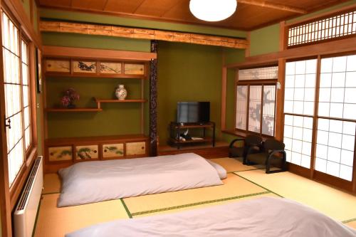 two beds in a room with green walls and windows at A large house with a beautifui Japanese-style room in Kurokawamachi