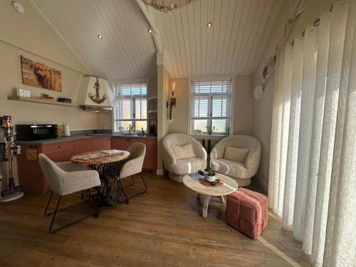 a living room with a table and chairs and a kitchen at Beach House Texel in De Koog