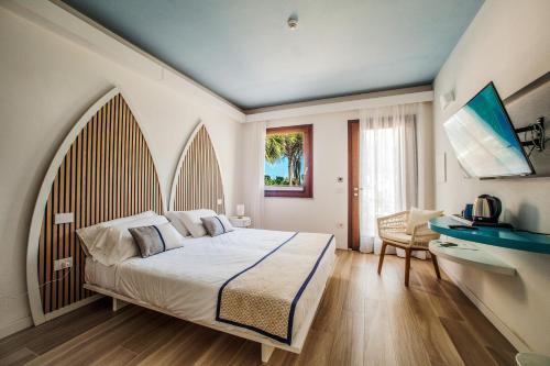 a bedroom with a large bed and a desk at Hotel New Barcavela in Santa Margherita di Pula