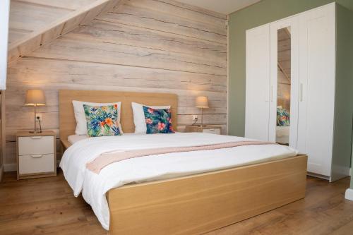 a bedroom with a large bed with wooden walls at Przy Rozlewisku in Sarbinowo
