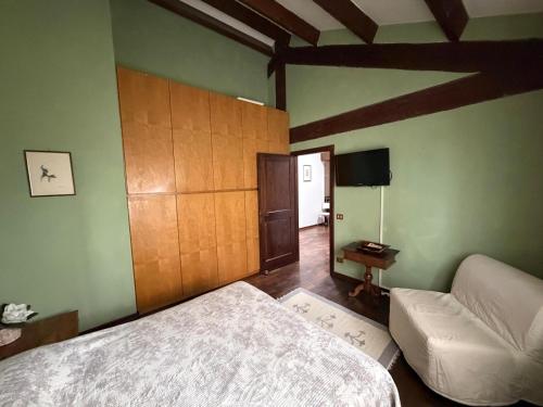 a bedroom with a bed and a couch and a television at Il Giardino di Dede in Ferrara