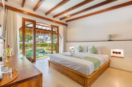 a bedroom with a large bed and a table at Roh Villas Kuta Lombok in Kuta Lombok