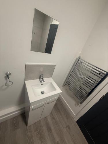 a white bathroom with a sink and a mirror at Pool table-Pet Friendly-Beach access-Garden in Trearddur