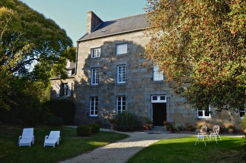 uma antiga casa de pedra com cadeiras brancas em frente em Maison de Benedicte em Saint-Brieuc