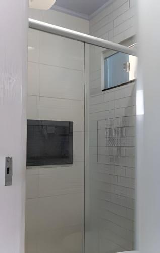 a glass shower in a bathroom with white tiles at Recanto Sol da Chapada | Aptos no Centro com Garagem e Café da Manhã in Alto Paraíso de Goiás