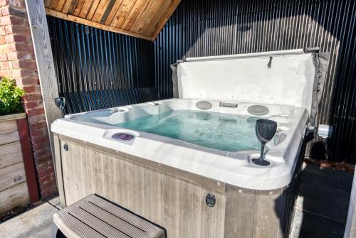 a jacuzzi tub with a wine glass in it at The Oak Sty - 2 Bed Countryside Cottage Escape in Durley with Hot Tub, Unique rural retreat, Private Parking, Sleeps 4 & Pet friendly - By Blue Puffin Stays in Southampton