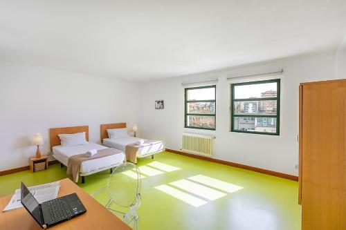 a room with two beds and a desk with a laptop at HI Castelo Branco - Pousada de Juventude in Castelo Branco