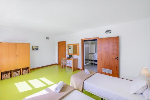 a room with two beds and a desk and a television at HI Castelo Branco - Pousada de Juventude in Castelo Branco