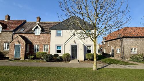 a house with a tree in front of it at Greenwich Cottage - Part of the The Bay Filey Holiday Village with pool, gym and direct beach access, pub, restaurant, tennis and meadows walks in Reighton