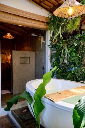 a bathroom with a bath tub with a green wall at Casa Preguiça Corumbau in Corumbau
