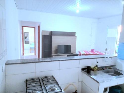 a white kitchen with a sink and a counter at Ambiente familiar em Poços de caldas in Poços de Caldas