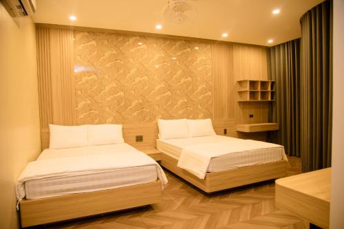 a bedroom with two beds and a wall at Mia Hotel Cửa Lò in Vinh