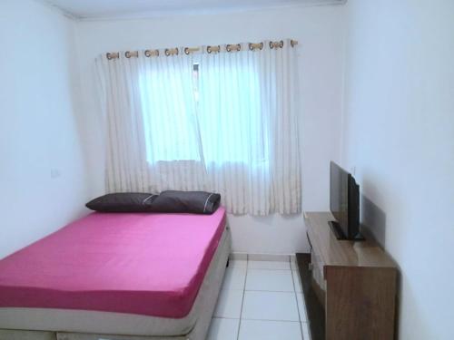 a small room with a bed and a tv at Ambiente familiar em Poços de caldas in Poços de Caldas