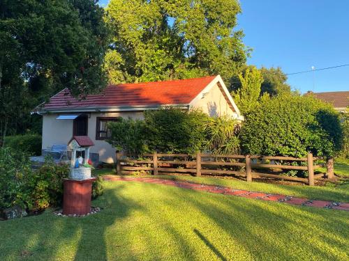 a small house with a wooden fence in a yard at Blue Crane Guesthouse in Hilton