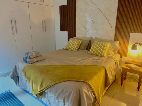 a bedroom with a large bed with yellow sheets and pillows at Blue Crane Guesthouse in Hilton
