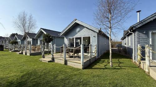 a blue house with a porch and a yard at Puffin Lodge - Part of the The Bay Filey Holiday Village with pool, gym and direct beach access, pub, restaurant, tennis and meadows walks in Filey