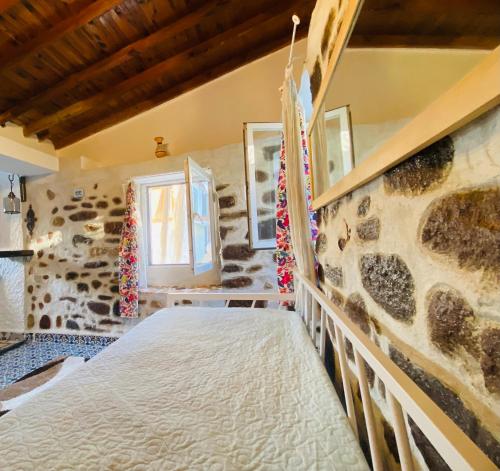 a bedroom with a bed in a stone wall at BadeHan Guest House in Çeşme