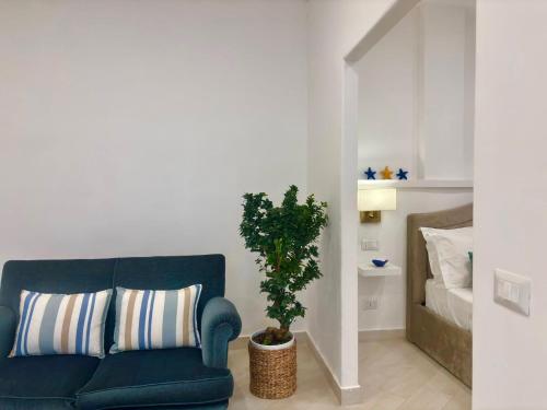 a living room with a blue couch and a plant at Syrene Suites Sorrento in Piano di Sorrento