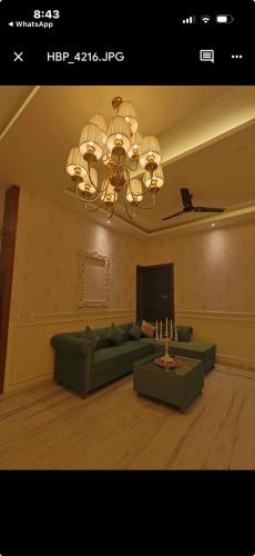 a living room with a green couch and a chandelier at Tiffany by SS castles in Sohāna