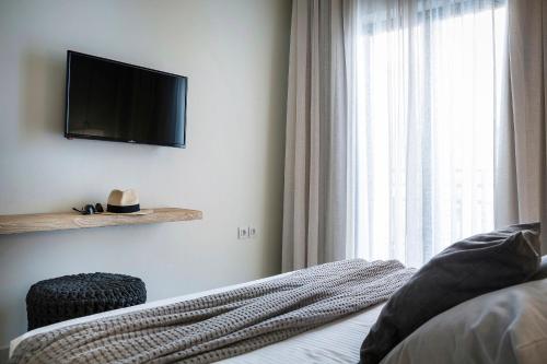 a bedroom with a bed with a television and a window at Kefalonia Grand in Argostoli