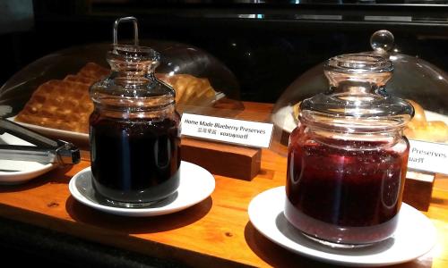 a jar of jam on plates on a table with waffles at Pacific Club Resort in Karon Beach