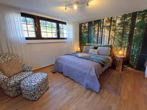 a bedroom with a bed and a chair and windows at ZusammenZeit in Schleiden - inklusive Sauna, Garage, großer Terrasse und 3 Schlafzimmer - ideal für Familien und Freunde - Hunde freundlich in Schleiden