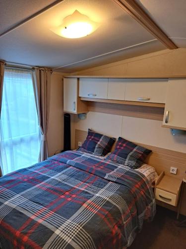 a bedroom with a bed with a plaid blanket at Cozy corner house, New vennepark in De Haan