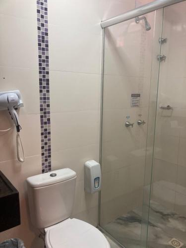 a bathroom with a toilet and a glass shower at Hotel Senador By Nobile in Quedas do Iguacu