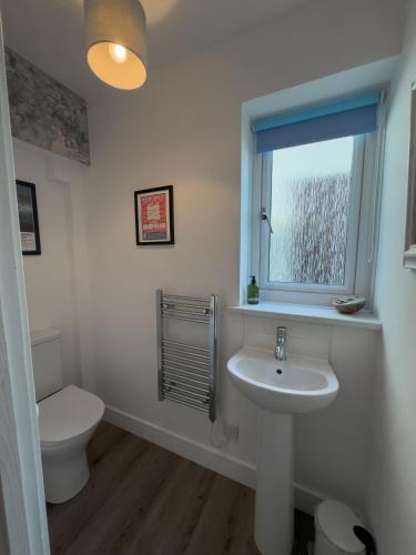 a bathroom with a toilet and a sink and a window at Beachcomber in Croyde