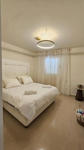 a bedroom with a large white bed with a light at Orins place eilat in Eilat