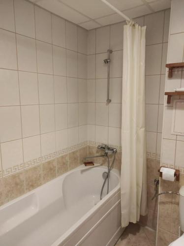 a bathroom with a bath tub with a shower curtain at Апартамент за гости Манчев in Stoykite