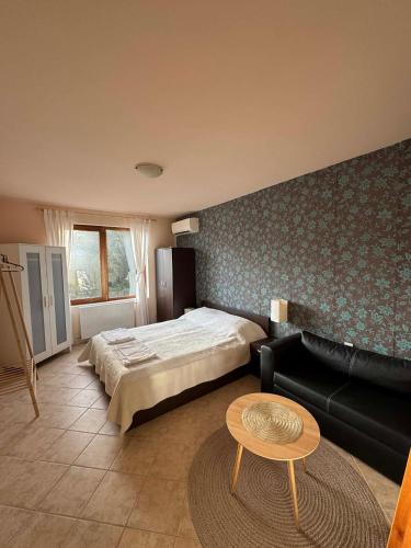 a bedroom with a bed and a couch and a table at Апартамент за гости Манчев in Stoykite
