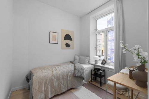 a white bedroom with a bed and a window at Prime Central Oslo - Frogner, All-Inclusive Apartment in Oslo