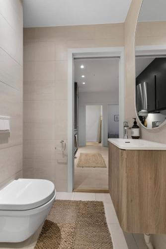 a bathroom with a toilet and a sink and a mirror at Prime Central Oslo - Frogner, All-Inclusive Apartment in Oslo