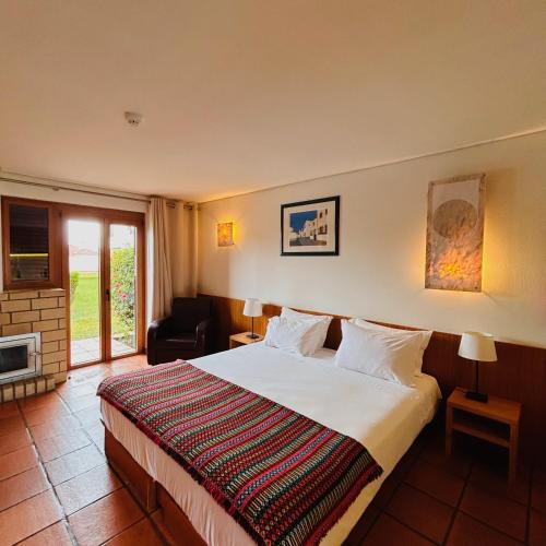 a hotel room with a bed and a fireplace at Hotel Apartamento Porto Covo in Porto Covo