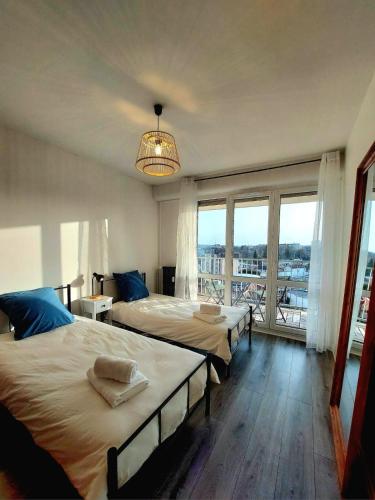 a bedroom with two beds and a large window at Appartement à Limoges, proche CHU in Limoges