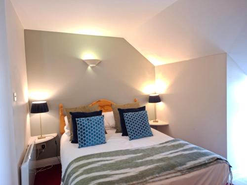 a bedroom with a bed with blue pillows and two lamps at Aran View Loft in Knockfin Cross Roads