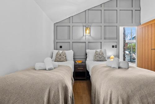 a bedroom with two beds and a wall with a window at The Oaks Barn - A Countryside Luxury Rural Escape with Hot tub & Fire Pit! Tranquil Group Retreat - Sleeps 8, Pet Friendly & Off road Parking - By Blue Puffin Stays in Southampton