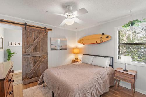 a bedroom with a bed and a surfboard on the wall at Sea Swept Cottage OBX in Kill Devil Hills
