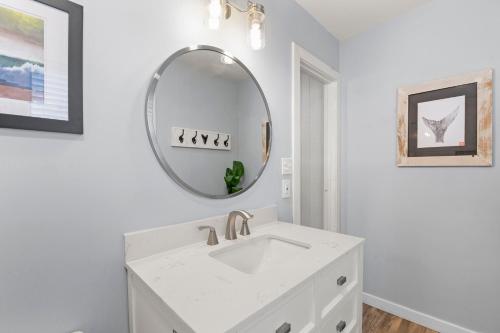a white bathroom with a sink and a mirror at Sea Swept Cottage OBX in Kill Devil Hills