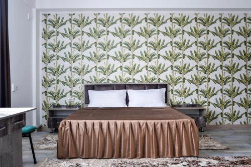 a bedroom with a bed and a wall with a wallpaper at KOLESEY Hotel in Taldykorgan