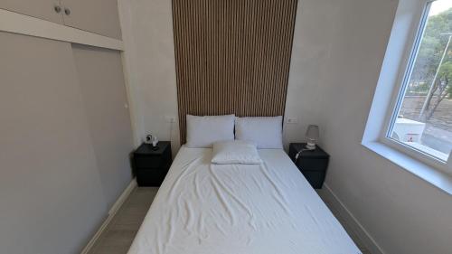 a small bedroom with a white bed with two night stands at Casa Ursula in Los Alcázares