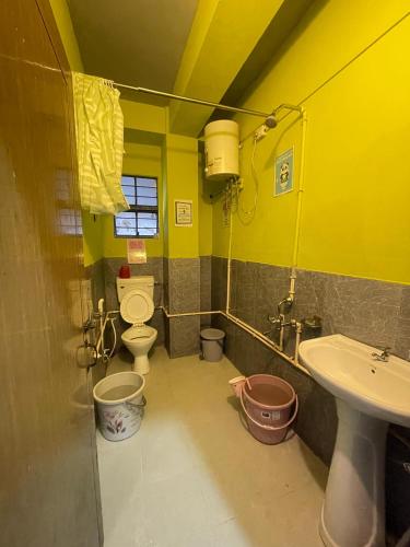 a yellow bathroom with a toilet and a sink at Hazz Backpackers Hostel in Shillong