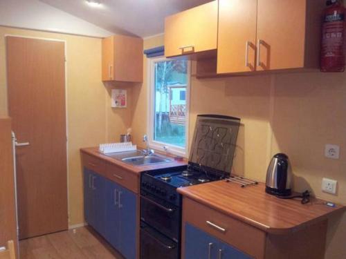 a small kitchen with a stove and a sink at Victoria Camping Bella Austria in Peterdorf