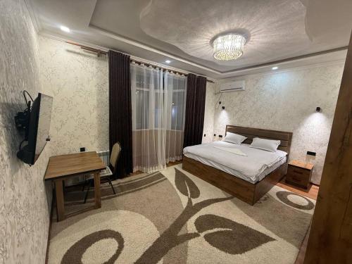 a bedroom with a bed and a table and a television at Guest house Homely in Dushanbe