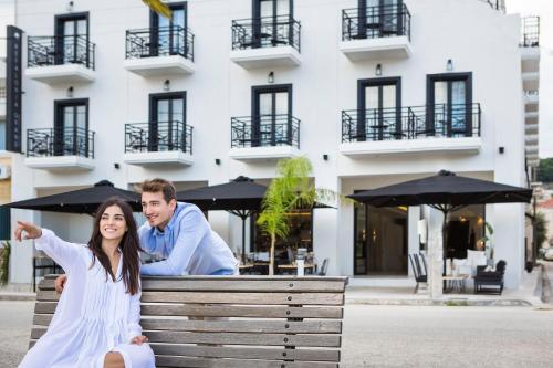 a man and a woman sitting on a bench in front of a building at Kefalonia Grand in Argostoli