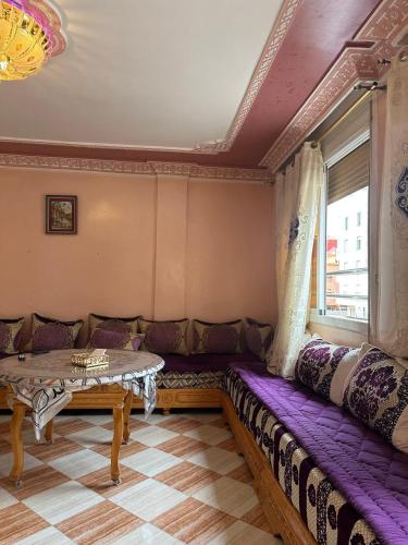 a living room with a purple couch and a table at Appartement champs élyséen in Berkane
