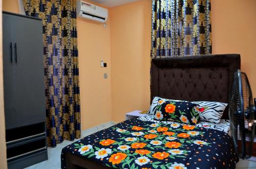 a bedroom with a bed with a floral comforter at New Benin Home in Benin City